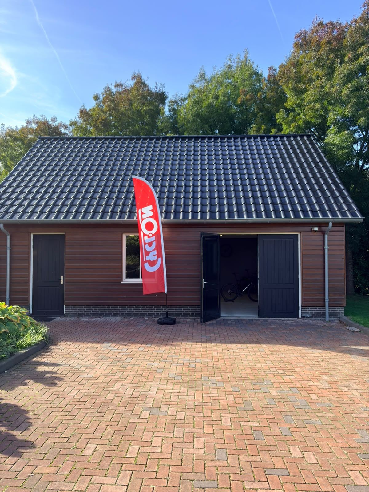 Werkplaats Van Steensel Wielersport — buitenkant van de werkplaats met openstaande deuren en een vlag